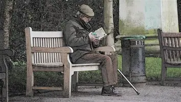 An elderly man with weathered hands and a warm smile sitting on a park bench